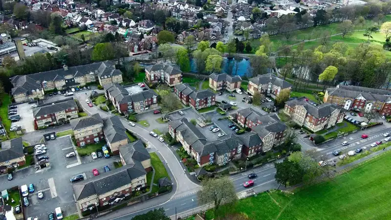 Aerial view of a modern housing estate with grey pitched roofs, cul-de-sacs and green space