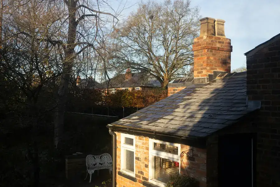 Brick house with a slate roof and tall chimney stack in low winter sun, similar to the 1920s colliery houses in Clipstone