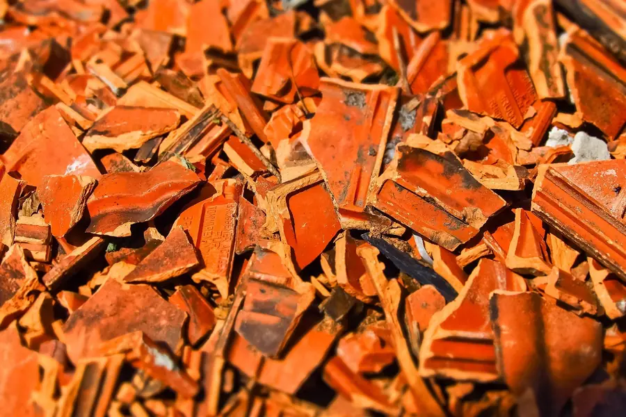 Pile of broken clay roof tiles stripped from an old roof, the kind of debris left after repairing a century-old pit village roof