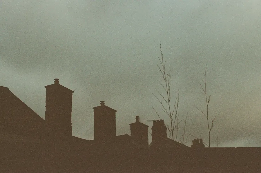 Row of chimney stacks silhouetted against a grey sky, like the shared stacks along terraced streets in Shirebrook
