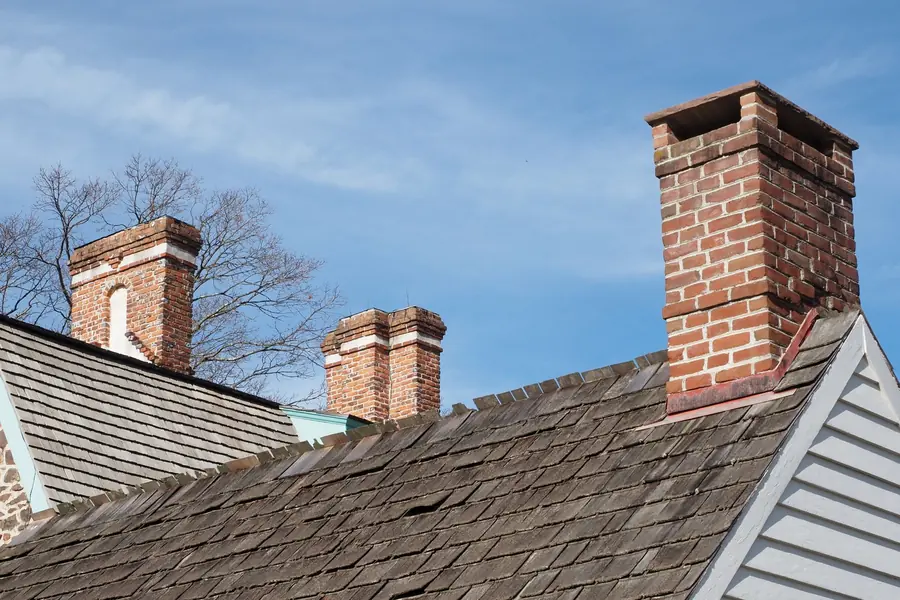 Brick chimney stacks with lead flashing rising through a pitched slate roof