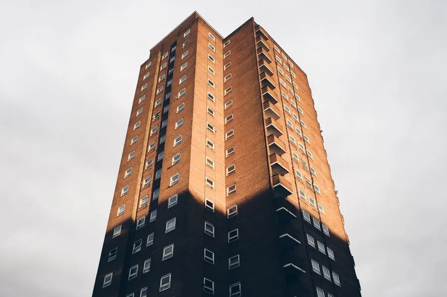 Low rise residential block of flats in brick, typical of ex council leasehold housing