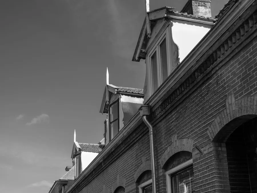 Row of dormer windows projecting from a brick building, the kind of high, exposed flat roof that needs scaffold to reach
