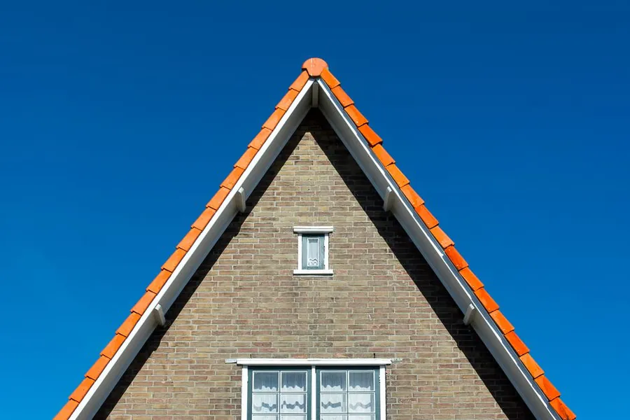 Brick gable end with red roof tiles and mortar bedded verge on a semi detached house