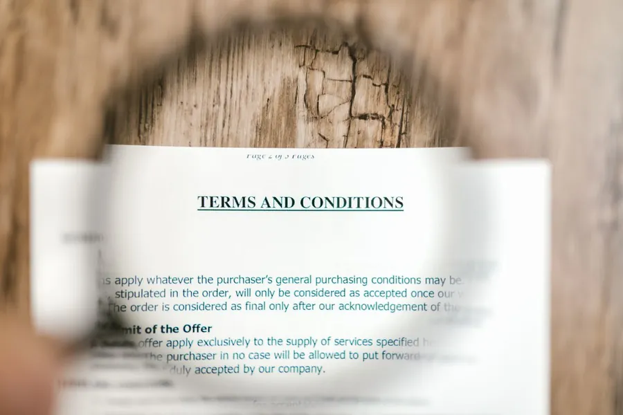 Magnifying glass over the terms and conditions of a roofing guarantee document for a Mansfield homeowner