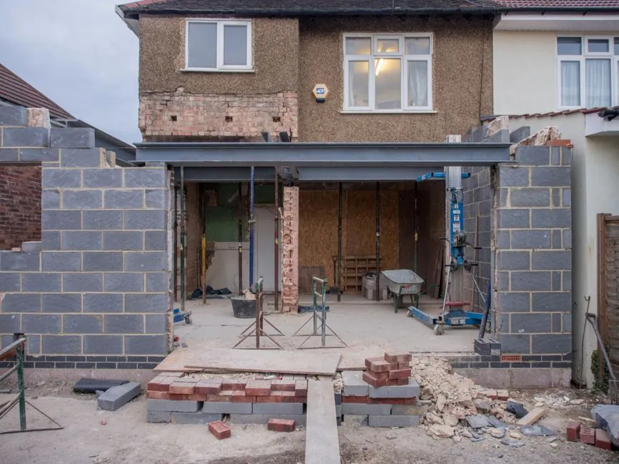 Brick house undergoing roofing and building work with scaffolding and materials on site