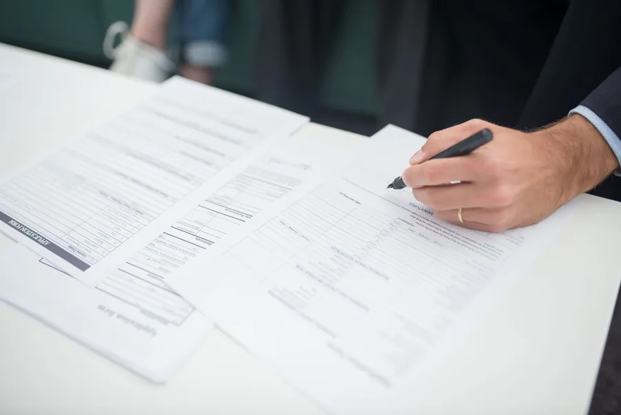 Hands completing a home insurance form at a desk with a pen