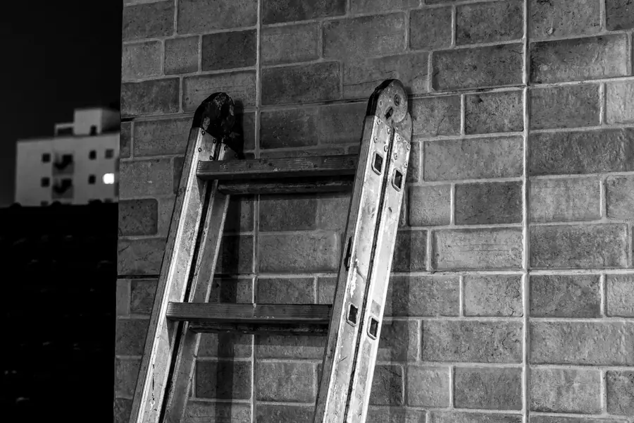 Extension ladder leaning against a brick wall at dusk ready for work at height