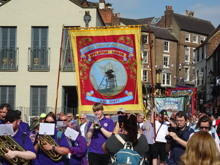 National Union of Mineworkers lodge banner carried with a brass band, a reminder of coalfield heritage shared by Sutton and Kirkby