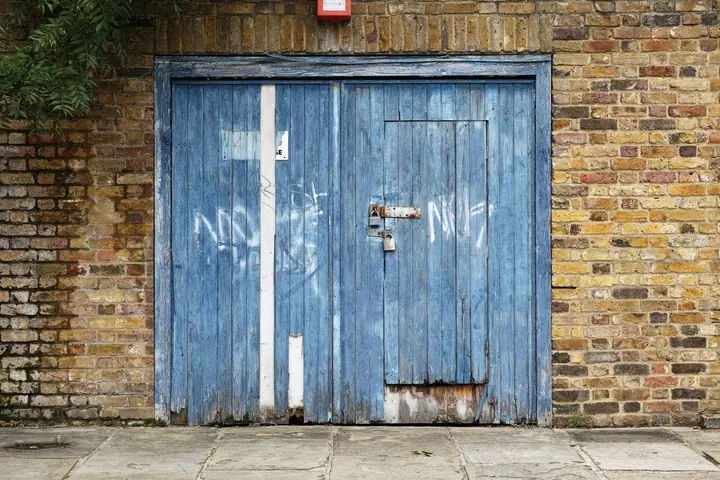 Weathered timber garage doors set in an old brick wall, typical of the detached garages behind older Mansfield houses