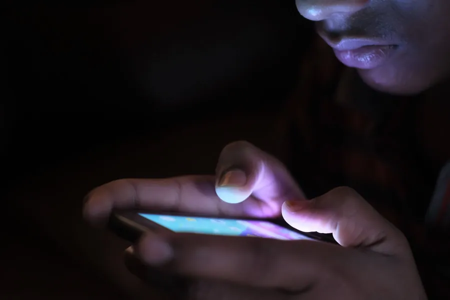 Person searching on a phone at night for an emergency roofer in Mansfield