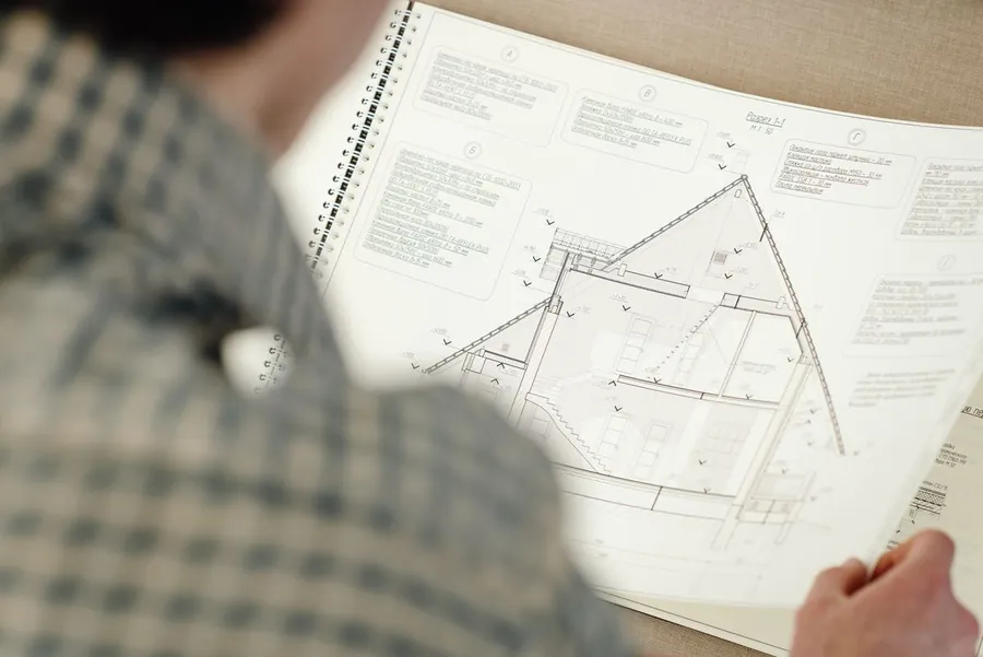 Someone reading a drawn cross-section of a pitched roof, the kind of drawing a re-roof application in Newark and Sherwood district can need