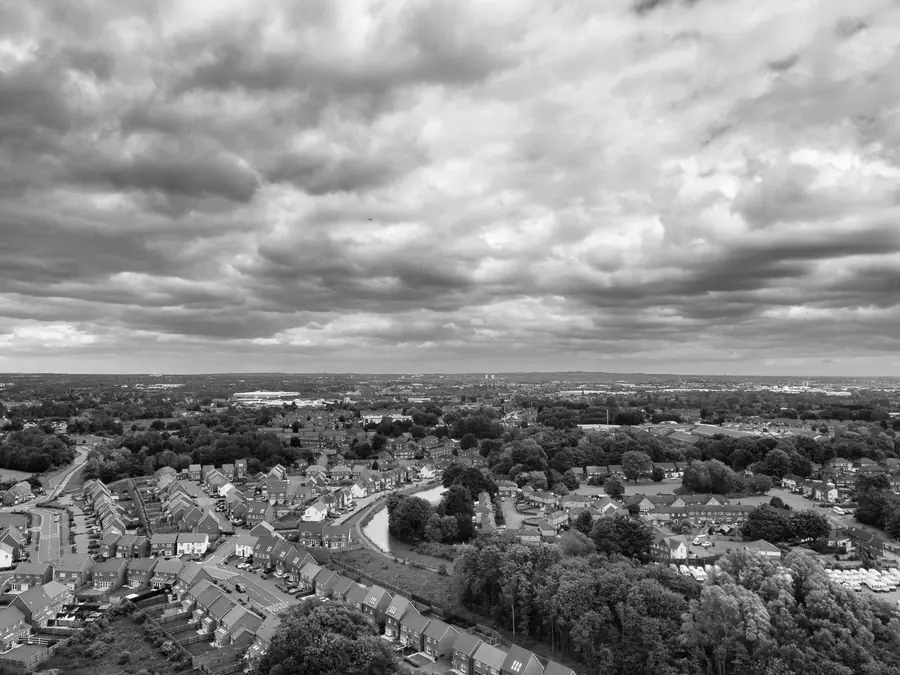 Black and white aerial view over postwar estate housing with rows of pitched concrete tile roofs, like the council estates around Mansfield