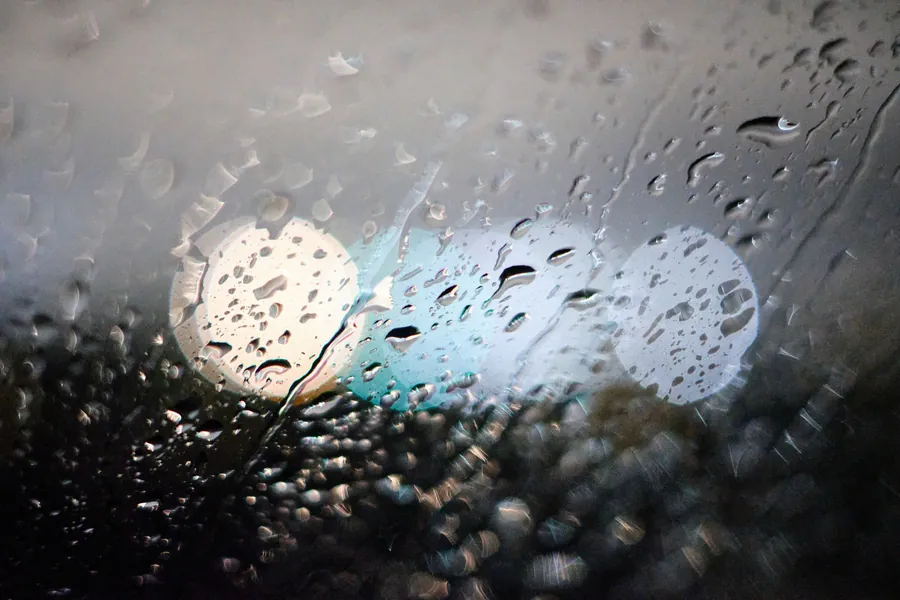Rain streaming down a window at night during an emergency roof leak in Mansfield
