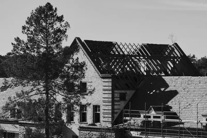 House with its roof covering stripped back to the rafters part way through a full re-roof