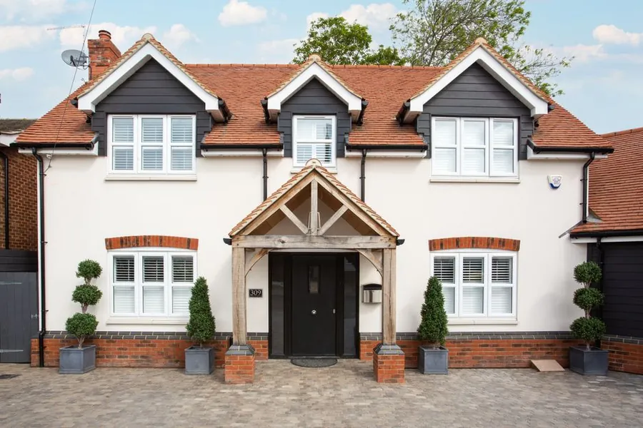Two storey brick house with a red tiled pitched roof, typical of ex council housing stock