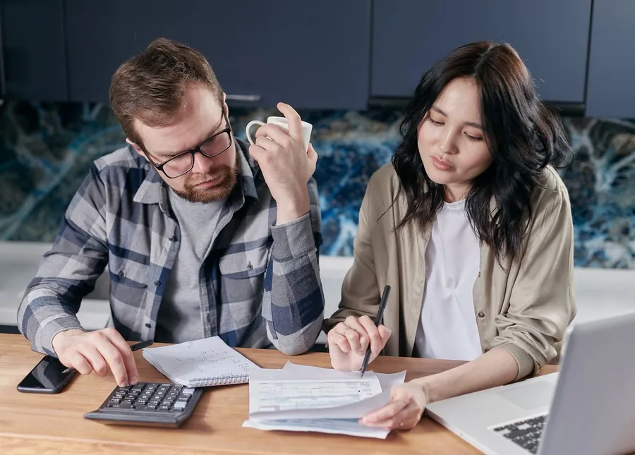 Couple at a kitchen table going through household bills and working out the cost of home repairs