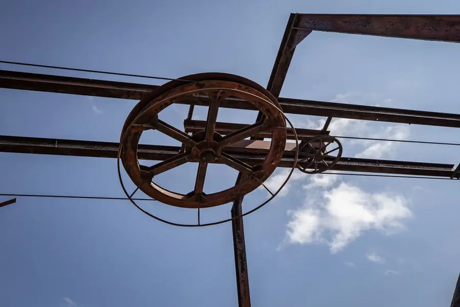 Rusting iron pulley wheel on a steel frame against the sky, like the winding gear that once stood over the Ollerton, Thoresby and Rufford pits