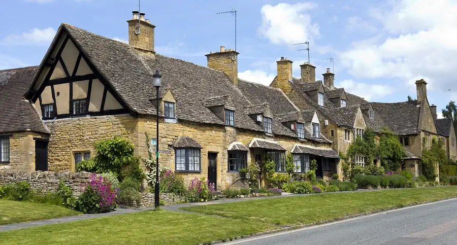 Row of old stone cottages with steep tiled roofs and chimneys along a village street