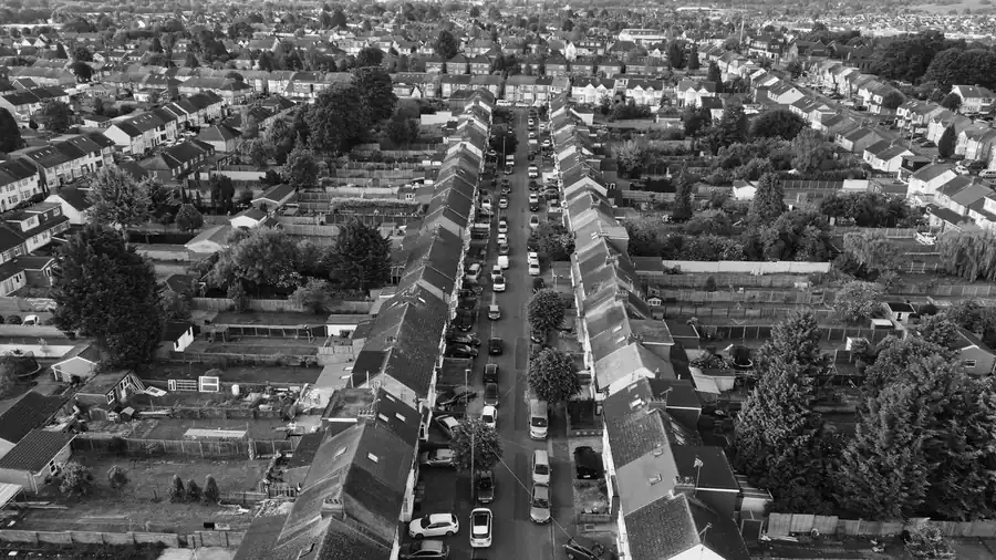 Black and white view along a British residential street of semis and terraces, where single slopes are often re-roofed separately in Mansfield