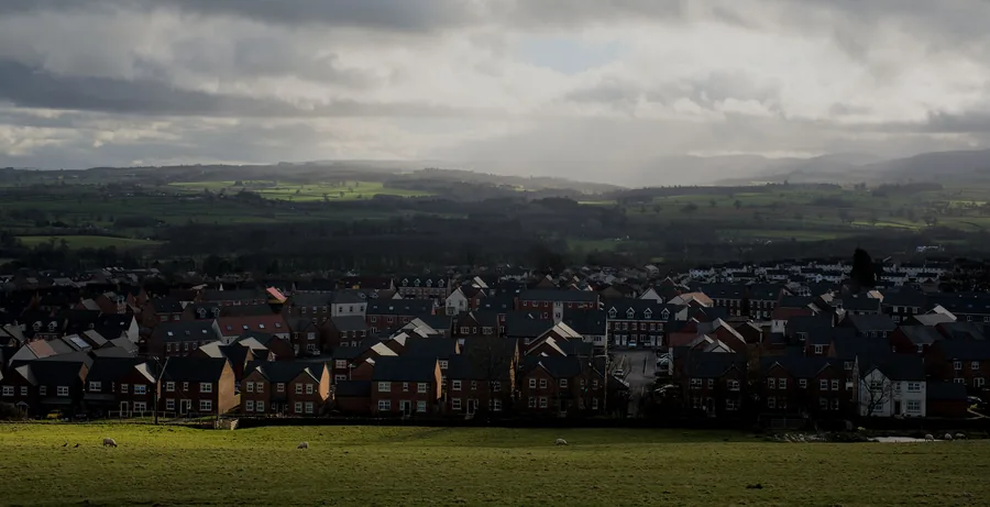 Rows of brick houses with grey tiled roofs on an estate below open hills, the kind of finished roof work a roofing guarantee in Mansfield is written against