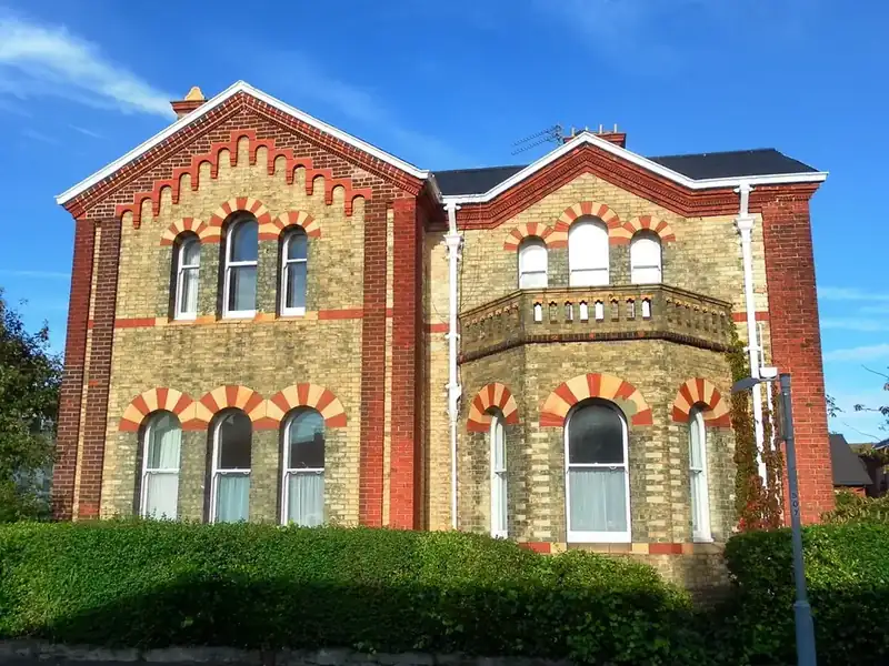 Victorian brick villa with decorative arched windows, a slate roof and chimney stacks