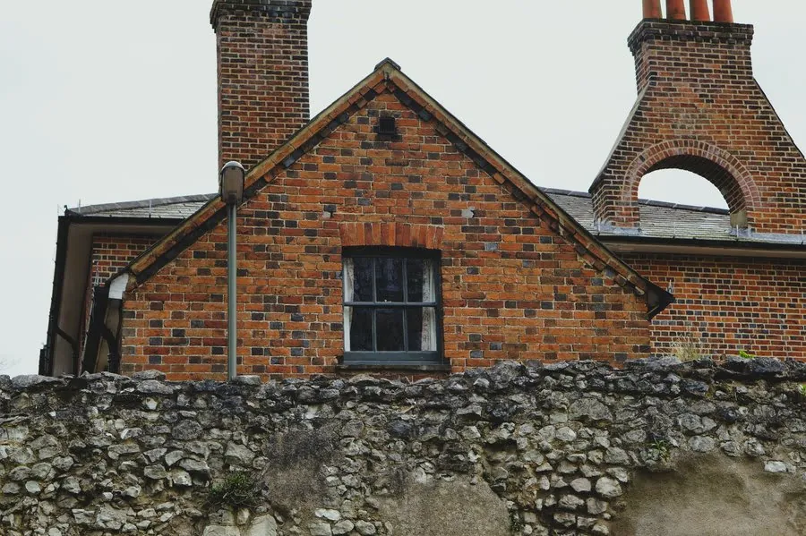 Red brick gable with tiled verge and ridge on an older house under a pale grey sky