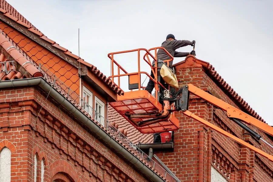 Roofer working along the ridge of a pitched tiled roof during a survey in Mansfield