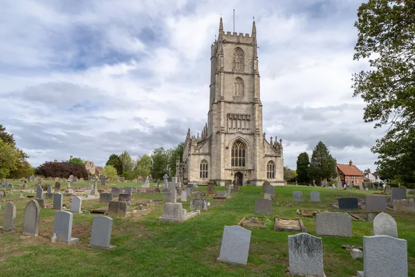 Stone church tower above an old English churchyard of upright headstones, similar to the setting of Blidworth parish church