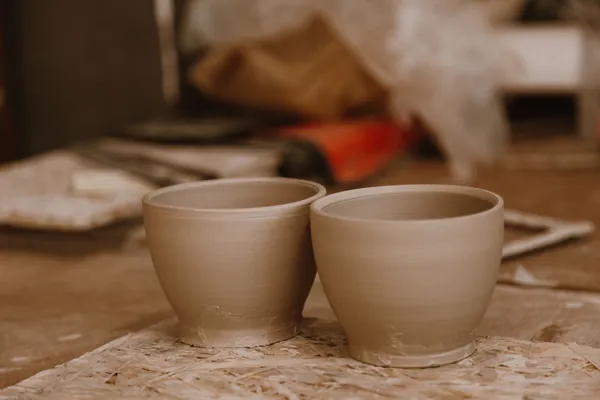 Two handmade clay pots on a workbench in a small craft studio, the kind of work sold at the art and craft centre in Edwinstowe