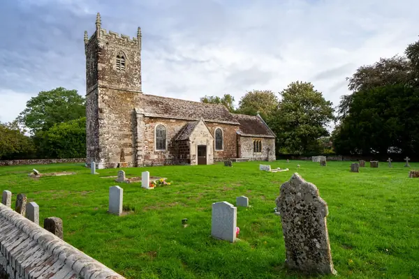 Medieval stone parish church with a square battlemented tower and a churchyard of old headstones
