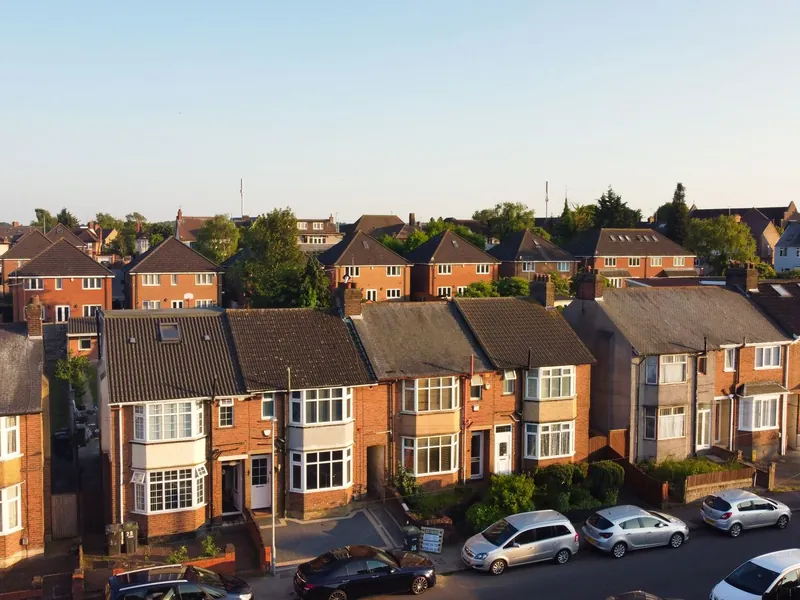 Aerial view of rows of brick semi-detached houses with hipped tiled roofs and parked cars, similar to the colliery-era streets of New Ollerton