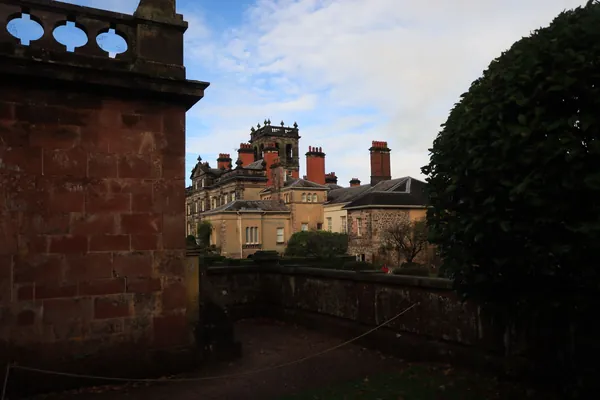 Red brick country house buildings with tall chimneys and a stone balustrade on an English estate, like the stable courtyard at Thoresby near Ollerton