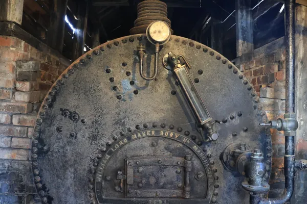Riveted Victorian steam boiler set into old brickwork, the type of industrial machinery preserved at colliery heritage sites like Pleasley Pit