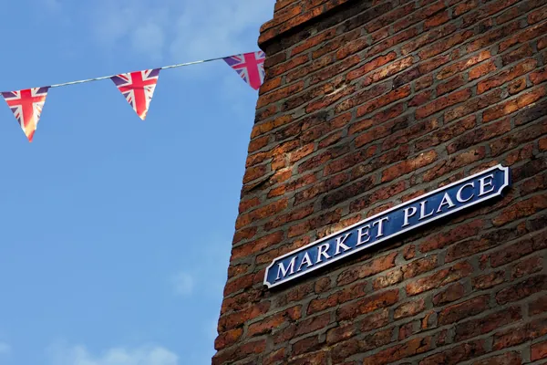 Blue Market Place street sign on an old red brick wall with Union Jack bunting overhead