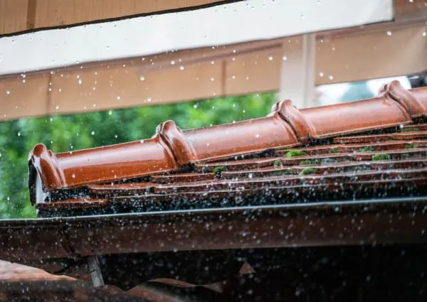 Rainwater pouring over the edge of a blocked gutter on a Mansfield house